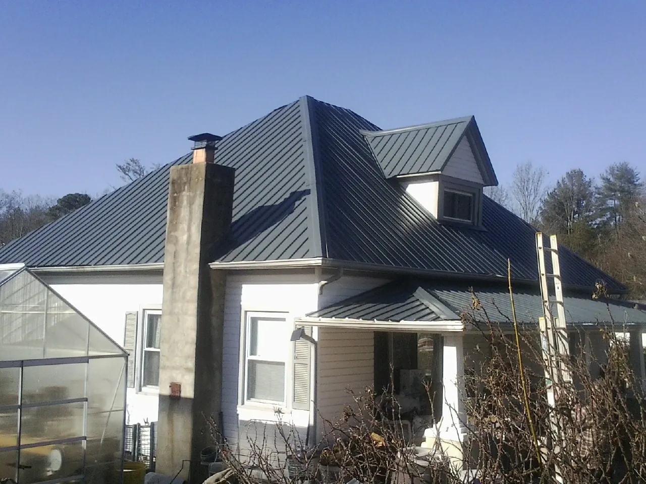 Dark blue standing seam metal roof on a white farmhouse with dormer — Slate & Tile Roof Repair by Roofing Brothers in Blenheim