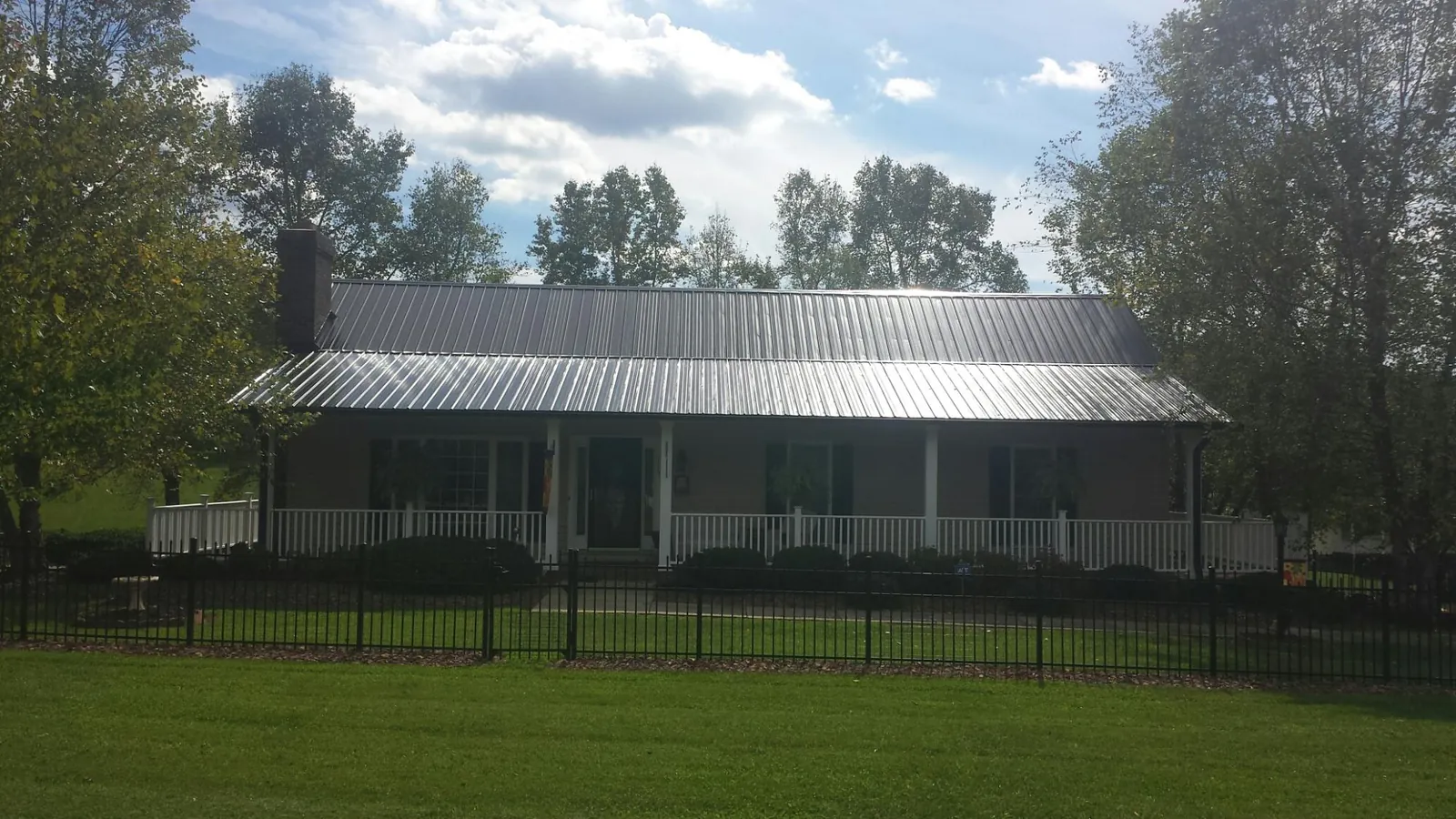 Gray metal roof on a brick ranch with a full width front porch — Gutter Guard Installation work by our crew in Blenheim