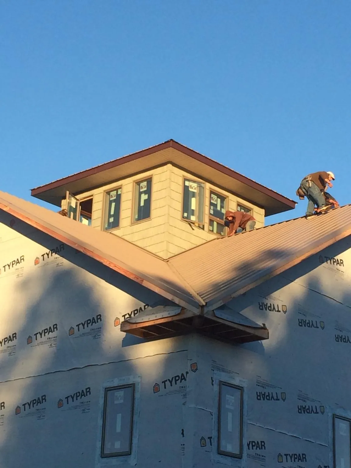 Roofers working around a rooftop cupola on a new metal roof at sunset — Roof Waterproofing in Blenheim by Roofing Brothers